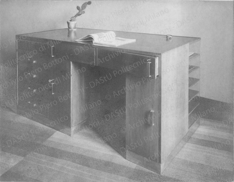 (Appartam. Ing.M. in Milano) Scrivania in noce naturale chiaro. Zoccolo in metallo bianco; piano superiore in linoleum; scomparti, armadietti, cassetti vari; ripiani con spalla in metallo; cassetti ruotanti che permettono di essere aperti senza spostamento della persona che siede davanti alla scrivania. Timbro a secco "Paoletti fotografo Milano". Positivo, bianco e nero, 159x204 mm, album giallo n.8, pag.67.