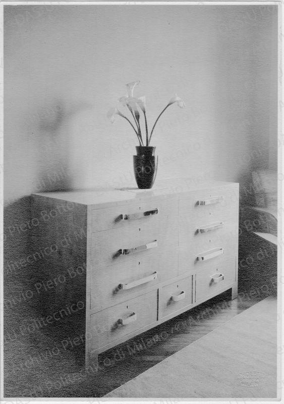 Veduta di canterale per camera da letto, positivo, bianco e nero, mm 219x151. Su una delle fotografie timbri ad inchiostro sul verso: "Piero Bottoni" e "La proprietà di questo modello è protetta a norma dell'art. 1 e seg. Del R. D. L. del 7 nov. 1925 n. 1950 sul diritto d'autore". Annotazione manoscritta sul verso: "Casa Minerbi in Milano. Canterale della camera da letto in acero grigio o rabano con finiture cromate. I cassetti inferiori sono ruotanti."