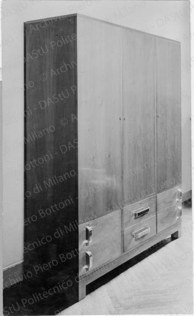 Mobile "per abiti e biancheria della signora", positivo, bianco e nero, mm 218x131. Timbro ad inchiostro sul verso: "Piero Bottoni". Annotazione dattiloscritta su carta velina incollata sul verso della fotografia: "Mobile in casa S. a Milano. In noce naturale chiaro, con maniglie in metallo cromato. Per abiti e biancheria della signora; specchi interni. Cassetti inferiori ruotanti".