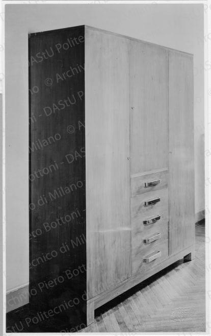 Mobile "per abiti e biancheria del signore", positivo, bianco e nero, mm 223x137. Su una fotografia timbri ad inchiostro sul verso: "Piero Bottoni" e "A. Paoletto - Fotografo. Via Pantano, n. 3 - Milano". Annotazione dattiloscritta su carta velina incollata sul verso della fotografia: "Mobile in casa S. a Milano. In noce naturale chiaro con maniglie in metallo cromato. Per abiti e biancheria del signore".