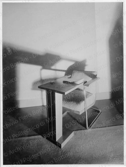 Veduta di "Poltrona in tubo di acciaio e legno di noce chiaro con imbottitura", positivo, bianco e nero, mm 227x171. Su una fotografia timbro ad inchiostro sul verso: "Da restituire" e "Piero Bottoni"; sull'altra La proprietà di questo modello è protetta a norma dell'art. 1 e seg. Del R. D. L. del 7 nov. 1925 n. 1950 sul diritto d'autore" e "Piero Bottoni". Su entrambe le fotografie annotazione dattiloscritta su carta velina incollata sul verso: "Poltrona in tubo di acciaio e legno di noce chiaro con imbottitura. Tavolino contrappesato per lettura o per servizio di tè. Questo tavolino è componibile con un altro identico in modo da formare un tavolino unico doppio con piede centrale".