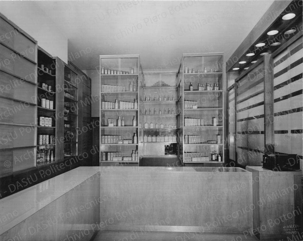 Veduta del banco di vendita e degli armadi dei medicinali. Timbro a secco "Paoletti fotografo Milano". Positivo, bianco e nero, 214x268 mm, album giallo n.6, pag.7.