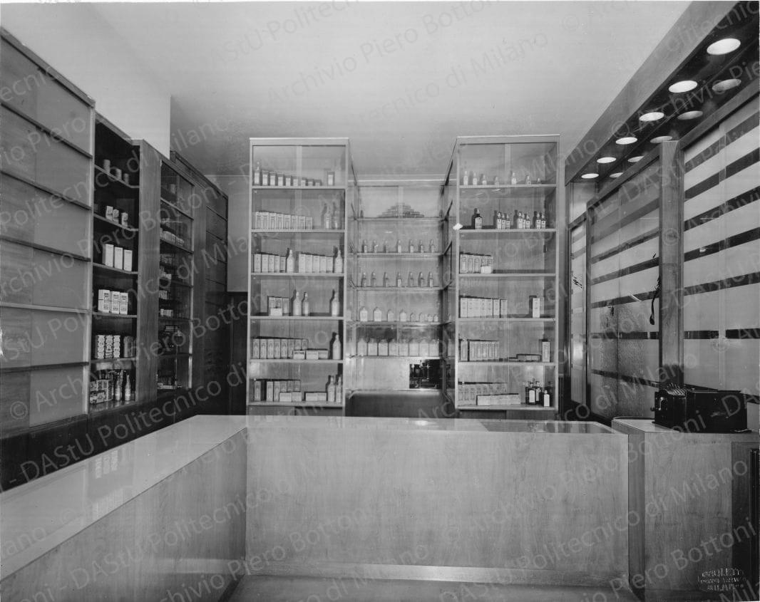Veduta del banco di vendita e degli armadi dei medicinali. Timbro a secco "Paoletti fotografo Milano". Positivo, bianco e nero, 214x270 mm, album giallo n.6, pag.8.
