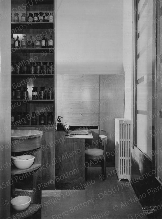 Veduta del retrobottega con la scrivania. Timbro a secco "Paoletti fotografo Milano". Positivo, bianco e nero, 225x167 mm, album giallo n.6, pag.10.