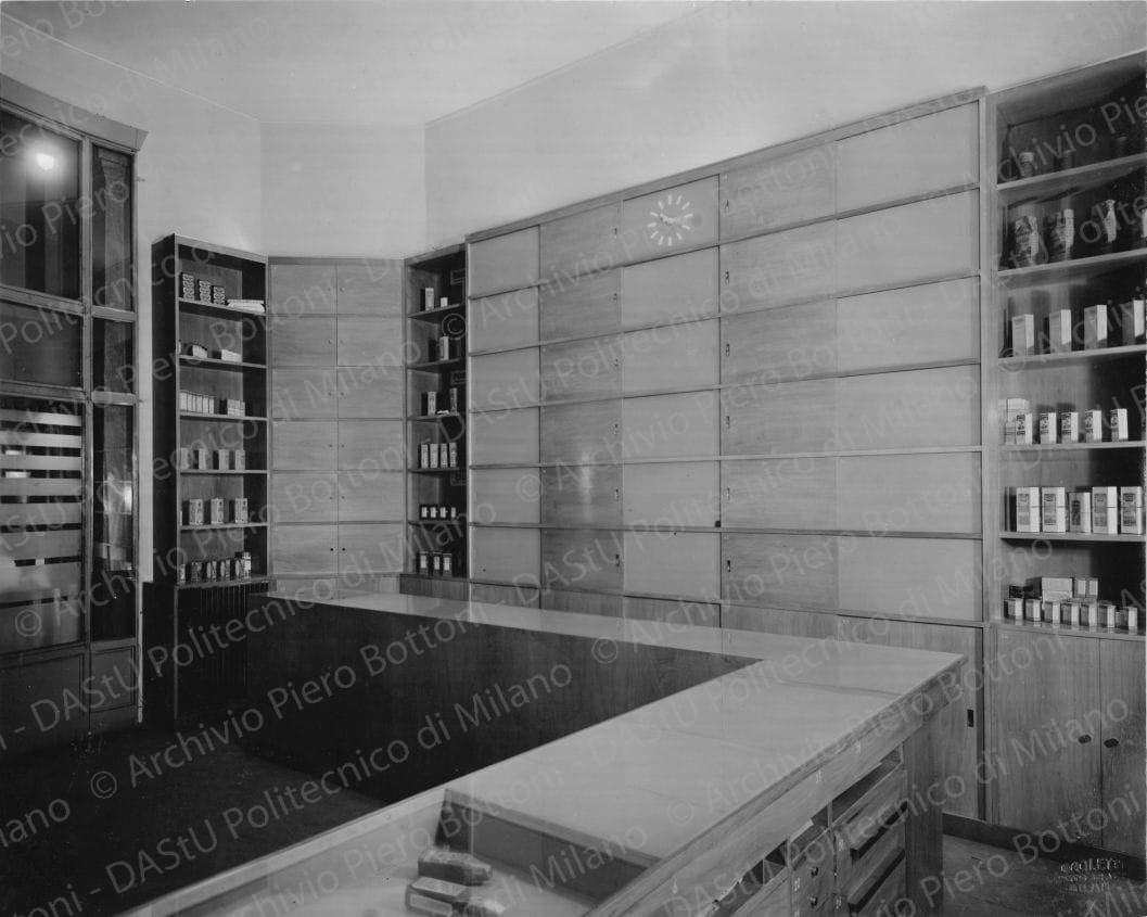Veduta del banco di vendita e degli armadi dei medicinali. Timbro a secco "Paoletti fotografo Milano". Positivo, bianco e nero, 215x268 mm, album giallo n.6, pag.12.