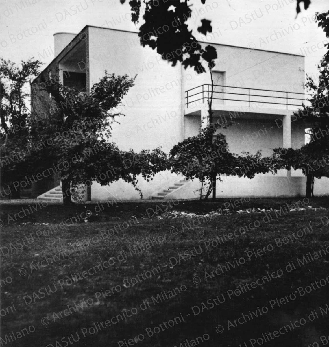 Veduta del prospetto nord-ovest. Didascalia dattiloscritta: "1934 - Casa di campagna a Reggio Emilia. Una plastica nuova in un tema tradizionale, interpretato con materiali tradizionali. Il grande locale soggiorno, in parte su due piani, finestrato sulle pareti opposte nel senso dei filari dei vigneti, cosicché la loro continuità sembri prospetticamente continuare nell'interno dell'edificio". Positivo, bianco e nero, 245x235 mm, album giallo n.19, pag.21.