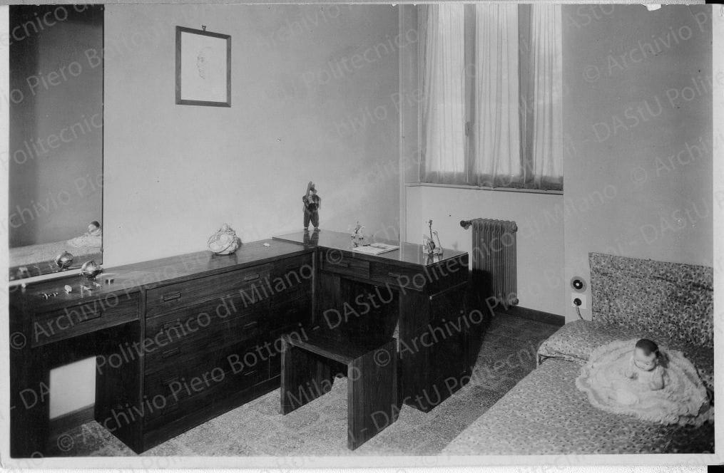 Veduta della "Camera della bambina", positivo, bianco e nero, mm 110x173. Timbri ad inchiostro sul verso: "Piero Bottoni" e "Da restituire". Annotazione manoscritta sul verso: "Camera della bambina. Nell'angolo a destra, dietro la testata del letto, è ricavata in una grande nicchia a muro la doccia. (Parte dell'arredamento già esistente)".