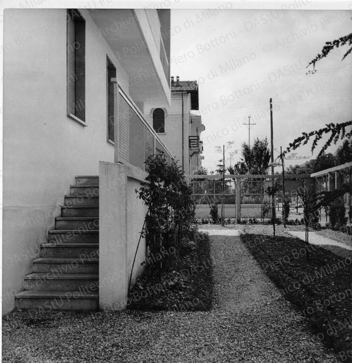 Idem, in formato differente, positivo, bianco e nero, mm 180x125.  Annotazione dattiloscritta sulvelina, incollata sul verso della fotografia: "...Un angolo della casa con vista del giardino recinto da telai in cemento armato e vista del terrazzo del piano terreno".