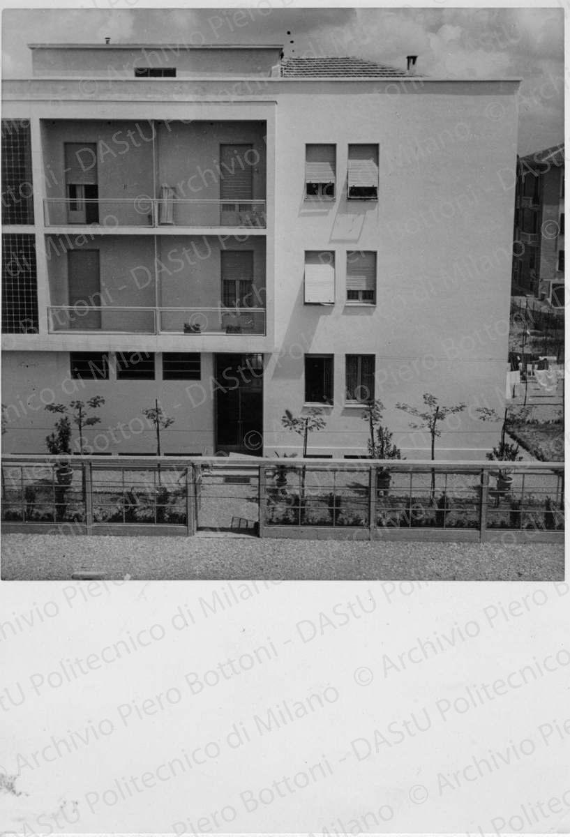 Idem, in formato differente, positivo, bianco e nero, mm 178x125. Annotazione dattiloscritta su velina incollata sul verso della fotografia: "...Fronte a sud con ingresso dalla strada a vista della recinzione in telai c.a.".