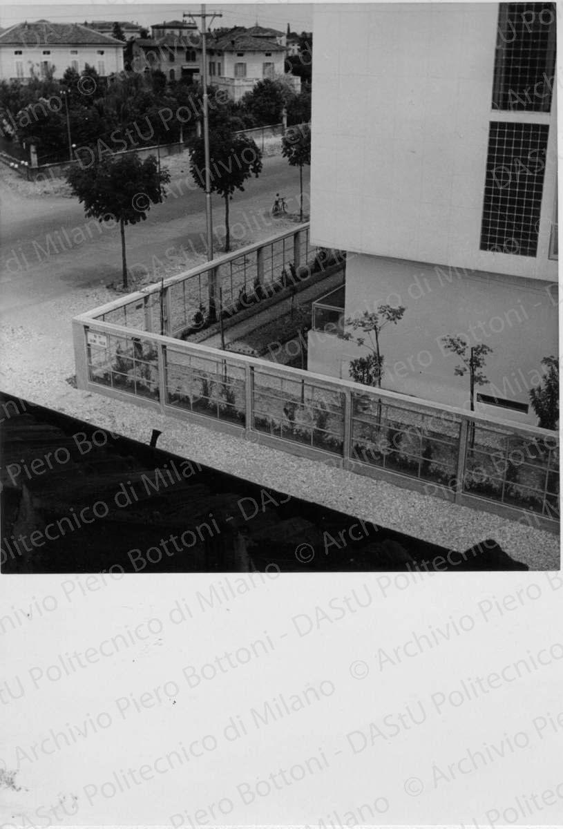 Idem, in formato differente, positivo, bianco e nero, mm 180x124. Annotazione dattiloscritta su velina incollata sul verso della fotografia: "...Dettaglio di un angolo della casa con il giardino e la recinzione. La grande finestrata in vetrocemento forma una parete fissa di illuminazione dei locali di soggiorno". 